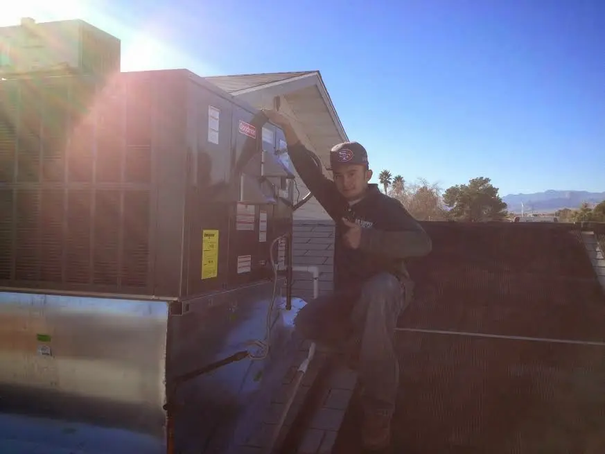 HVAC technician performing AC Tune-Up on a rooftop unit in Honeygo